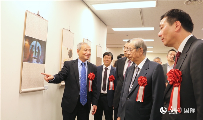 “湖州印象”攝影展主創(chuàng)、世界華人攝影協(xié)會(huì)副會(huì)長(zhǎng)馮學(xué)敏向吳江浩大使、福田康夫前首相等嘉賓介紹展出作品。（人民網(wǎng) 許可攝）