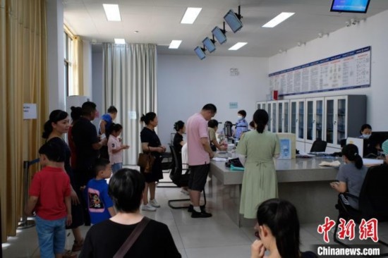 圖為在戶籍辦證廳內(nèi)排隊等待的家長和孩子。劉俊聰 攝