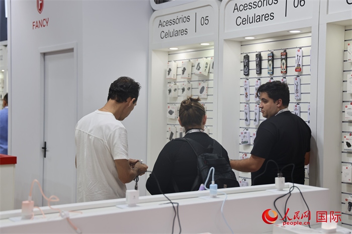 幾名參觀者在一個展臺前了解手機(jī)配件。（人民網(wǎng)記者 時元皓攝）