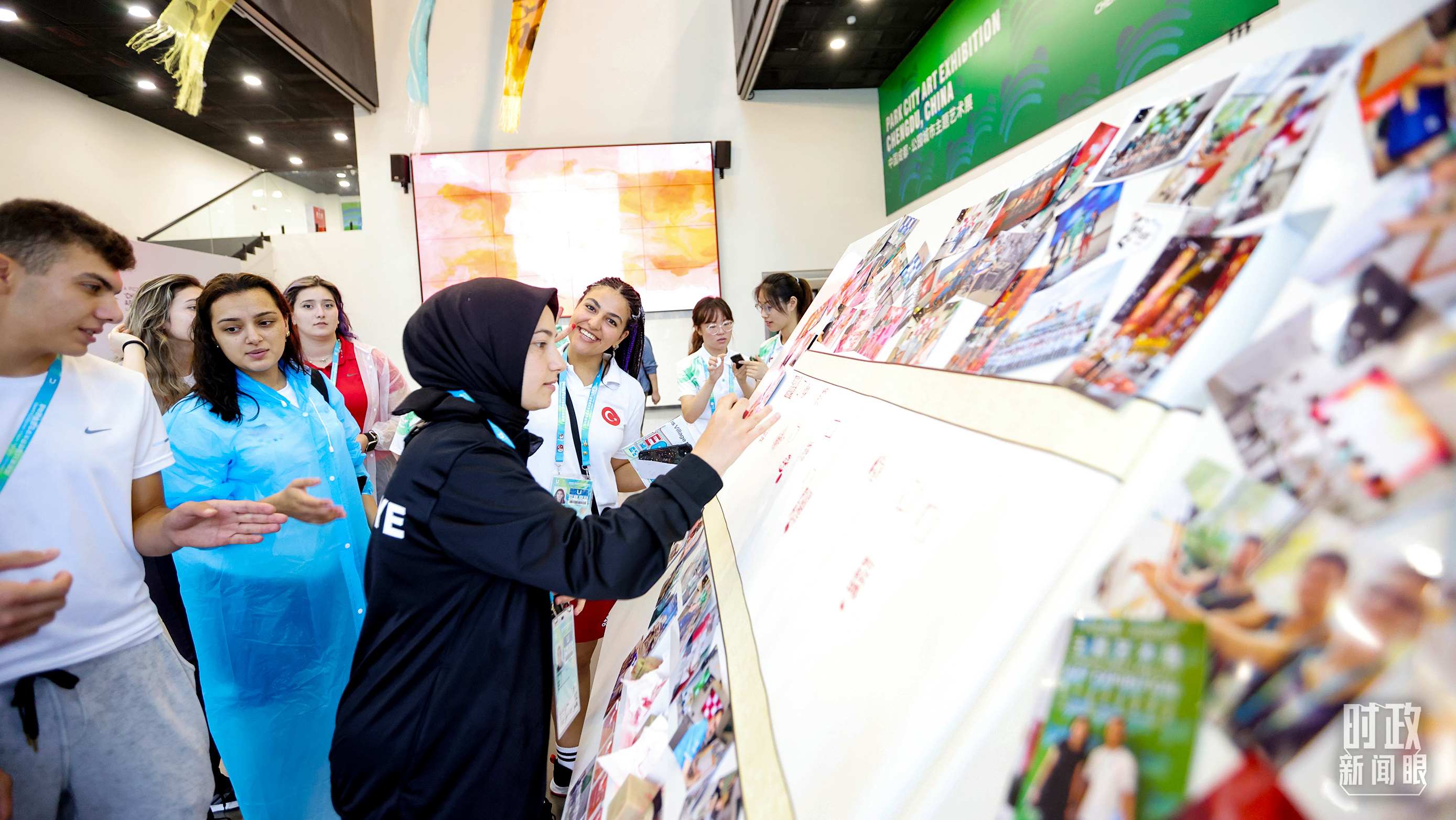 各國(guó)青年運(yùn)動(dòng)員正在參觀成都大運(yùn)村內(nèi)的“雪山下的公園城市，煙火里的幸福成都”主題藝術(shù)展。（總臺(tái)央視記者魏幫軍拍攝）