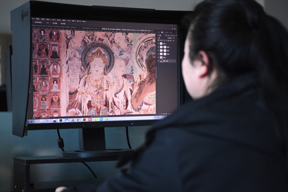 敦煌研究院文物數(shù)字化保護團隊圖像處理人員年海麗在拼接壁畫圖像（2023年4月25日攝）。數(shù)字化探索為莫高窟的保護與傳承開辟了全新路徑，數(shù)字技術(shù)讓敦煌文物走出洞窟，跨出國門，走向“永久保存、永續(xù)利用”。新華社記者 陳斌 攝