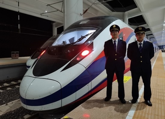 劉銀能（右一）與中國(guó)師父鄔俊鴻在動(dòng)車組前合影。受訪者供圖