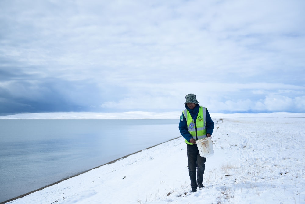 2021年10月20日，在青海省果洛藏族自治州瑪多縣扎陵湖鄉(xiāng)勒那村，三江源國家公園黃河源園區(qū)生態(tài)管護(hù)員在扎陵湖邊撿拾垃圾。新華社記者 張龍 攝