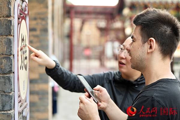 選手安德烈（俄羅斯）在老師指導(dǎo)下學(xué)習(xí)墻壁上張貼的生僻字。人民網(wǎng) 盧鵬宇攝