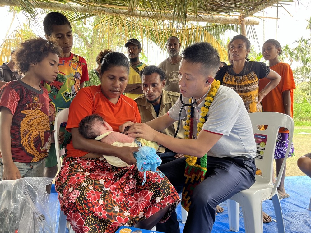 2023年8月5日，在巴布亞新幾內(nèi)亞中央省的一個(gè)村莊里，第12批援巴新中國(guó)醫(yī)療隊(duì)副隊(duì)長(zhǎng)、新生兒科副主任醫(yī)師劉振球?yàn)楫?dāng)?shù)貗雰郝?tīng)診檢查。新華社發(fā)（第12批援巴新中國(guó)醫(yī)療隊(duì)供圖）
