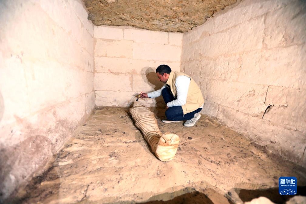 10月15日，在埃及明亞省考古現(xiàn)場，考古人員清理一座石鑿墓中的木乃伊。新華社發(fā)（艾哈邁德·戈馬攝）