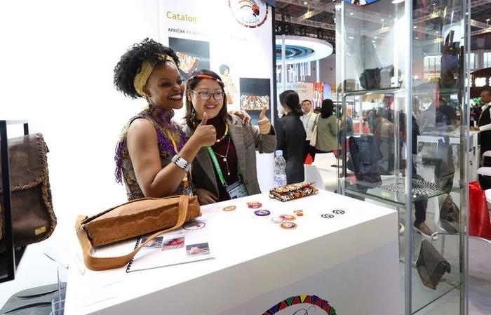 11月6日，一位參觀者（右）在第六屆進(jìn)博會(huì)國(guó)家展南非展臺(tái)試戴傳統(tǒng)首飾。