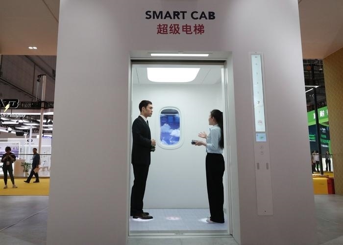 11月5日，工作人員（右）在第六屆進(jìn)博會(huì)上向參觀者介紹奧的斯公司全新推出的超級(jí)電梯。