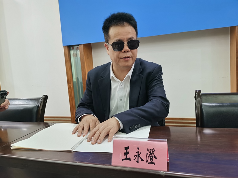 全國(guó)人大代表王永澄正在閱讀盲文版代表建議答復(fù)。本報(bào)記者 張 璁?dāng)z