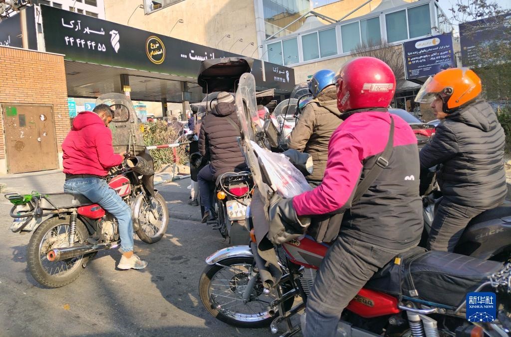 12月18日，摩托車在伊朗首都德黑蘭的一家加油站外等待加油。新華社記者 沙達提 攝