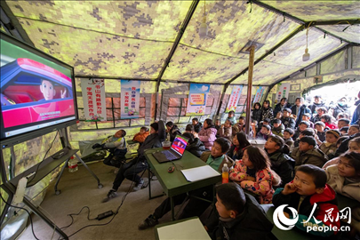 12月22日，在積石山縣大河家鎮(zhèn)大河村安置點(diǎn)，陸軍76集團(tuán)軍某旅搭建的“臨時(shí)學(xué)?！眱?nèi)，小朋友正在看動(dòng)畫片。人民網(wǎng)記者 翁奇羽攝