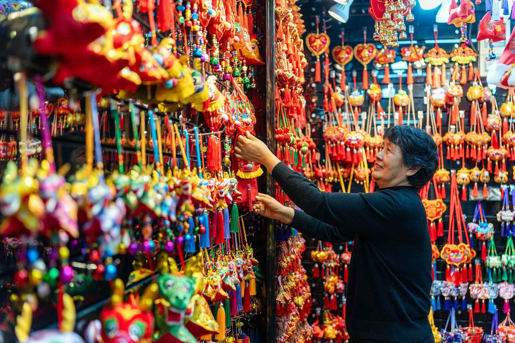 2023年12月11日，金華義烏國際商貿(mào)城，龍年喜慶用品掛滿攤位，顧客正在挑選中。