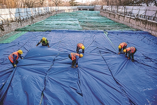 1月3日，房山區(qū)東風(fēng)街道，工人正在修復(fù)的河道內(nèi)給混凝土鋪設(shè)保溫布。
