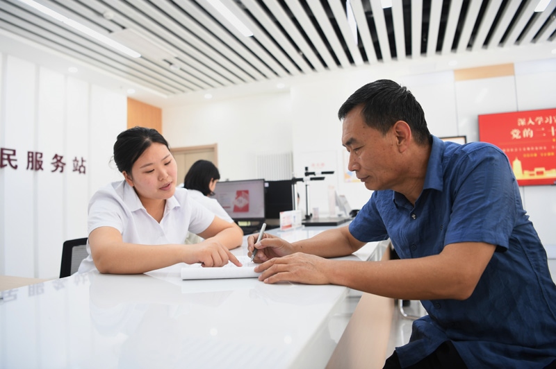 2023年5月23日，河北雄安新區(qū)容東片區(qū)南文營社區(qū)居民（右）在社區(qū)便民服務站辦理業(yè)務。