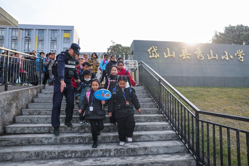 2023年12月20日，秀山派出所民警在秀山小學(xué)放學(xué)時(shí)間參與“護(hù)學(xué)崗”維持秩序，同時(shí)接獨(dú)自放學(xué)的學(xué)生去“民生小鋪”。浙江省舟山市岱山縣公安局秀山派出所聯(lián)合鄉(xiāng)鎮(zhèn)、社區(qū)成立“民生小鋪”，為當(dāng)?shù)鼐用?、外?lái)務(wù)工人員及其子女等服務(wù)，協(xié)助解決外來(lái)務(wù)工人員在工作、生活等方面的矛盾和問(wèn)題，助力鄉(xiāng)鎮(zhèn)基層治理。新華社記者 徐昱 攝