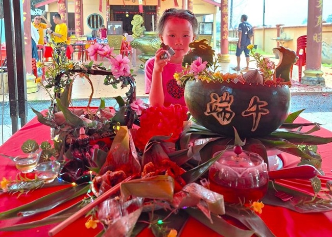 小朋友展示學(xué)裹粽子的成品照。組委會供圖