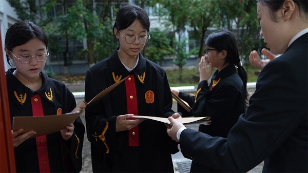 圖①：武平法院干警向學生分發(fā)道具卷宗。