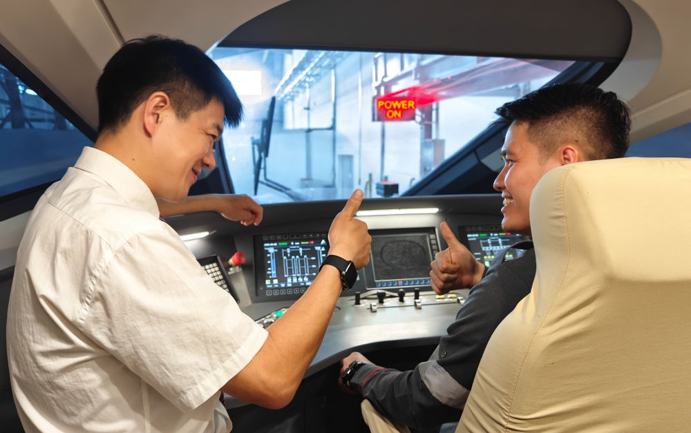 2023年8月25日，在印度尼西亞萬隆的雅萬高鐵德卡魯爾動車所內(nèi)，中國師傅穆振（左）向印尼火車司機塞蒂亞萬講解動車組出庫前的上電作業(yè)。新華社記者 徐欽 攝