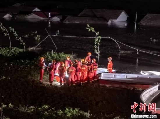  7月6日凌晨3時(shí)，在湖南岳陽(yáng)華容縣團(tuán)洲垸洞庭湖一線堤防，救援人員剛剛完成一次救援任務(wù)，遠(yuǎn)處是被淹的民房。中新社記者 白祖偕 攝