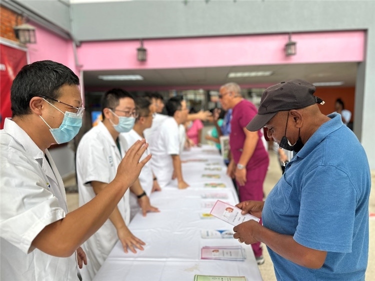 援圭醫(yī)療隊(duì)隊(duì)員們在啟動(dòng)儀式上為當(dāng)?shù)孛癖姺职l(fā)宣傳手冊。中國援助圭亞那醫(yī)療隊(duì)供圖