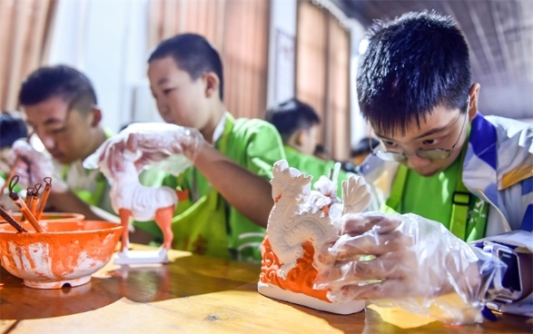 小朋友們在洛陽市孟津區(qū)朝陽鎮(zhèn)南石山村體驗唐三彩素胎施釉技藝。圖片來源：視覺中國