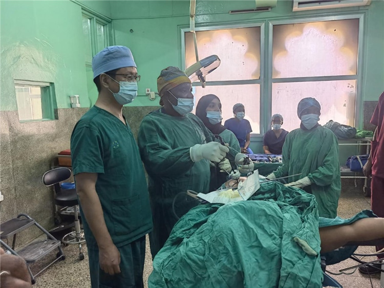 隊(duì)長蔣國慶（左一）關(guān)注當(dāng)?shù)蒯t(yī)生手術(shù)情況。中國援桑醫(yī)療隊(duì)供圖