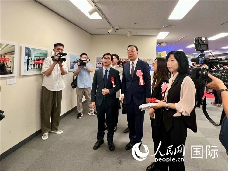 中國國際航空日韓地區(qū)支社支社長馮力為中國駐日本大使館臨時(shí)代辦施泳等嘉賓介紹展出圖片。人民網(wǎng) 許可攝