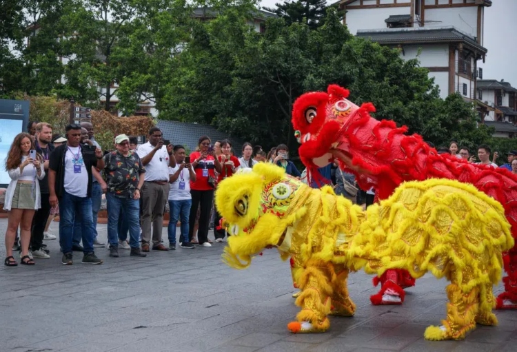 2024“一帶一路”媒體合作論壇聯(lián)合采訪調(diào)研行成員在樂(lè)山蘇稽古鎮(zhèn)觀看非遺舞獅表演。本報(bào)記者 伊霄攝