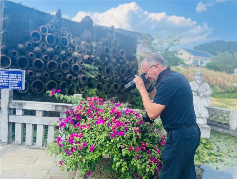 遠處黔北民居錯落有致，近處一只黑色的蝴蝶穿梭于粉紫色三角梅花叢間隙，與俄羅斯“大歐亞”總編輯弗拉基米爾·別列日內赫的鏡頭玩起了捉迷藏，“你追我逃，不亦樂乎”。（張亞欣攝）