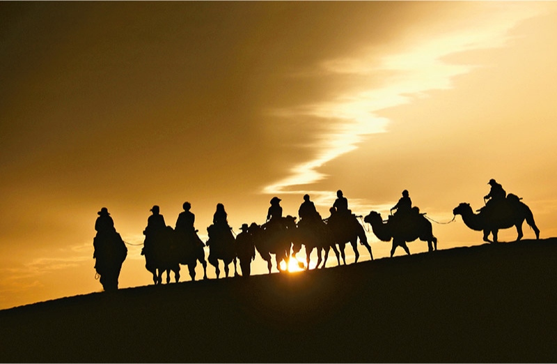 新時代以來，文化和旅游深度融合發(fā)展體制機制不斷健全，成功走出了一條獨具特色的中國旅游發(fā)展之路。圖為2024年9月1日清晨，游客在甘肅省敦煌市鳴沙山月牙泉景區(qū)乘騎駱駝，欣賞大漠風光，體驗絲路風情。 新華社發(fā) 張曉亮/攝