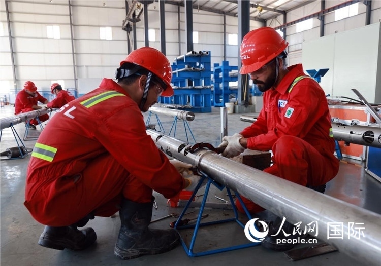 中伊員工共同在檢修鉆井設(shè)備。人民網(wǎng)記者管克江攝