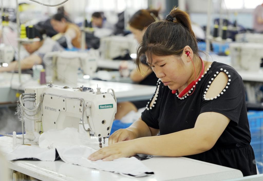 5月20日，村民在李寨村服裝加工廠內(nèi)忙碌。河南省周口市沈丘縣馮營鎮(zhèn)李寨村地處豫東平原。近年來，乘著脫貧攻堅與鄉(xiāng)村振興政策的東風(fēng)，李寨村積極探索產(chǎn)業(yè)發(fā)展模式，通過“龍頭企業(yè)+村集體經(jīng)濟+農(nóng)戶”的方式，逐漸發(fā)展形成肉牛養(yǎng)殖、設(shè)施農(nóng)業(yè)、服裝加工、康養(yǎng)民宿等產(chǎn)業(yè)，以產(chǎn)業(yè)振興助力鄉(xiāng)村振興。新華社記者 李嘉南 攝