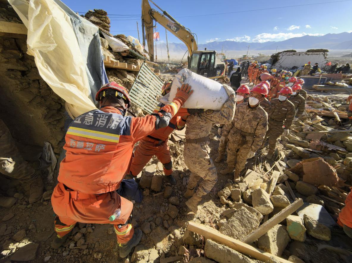 1月11日，定日縣長所鄉(xiāng)古榮村，應(yīng)急消防等救援人員排隊接力搶運掩埋在倒塌房屋下的群眾財物。人民日報記者楊翹楚攝