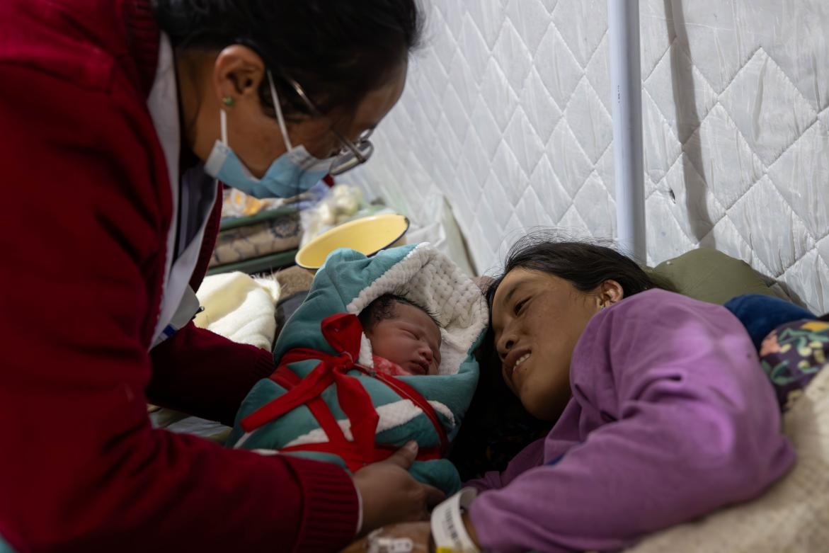 1月10日，定日縣中心醫(yī)院的婦產(chǎn)科醫(yī)生悉心照看一位母親和她懷里的新生兒。人民日報記者張武軍攝