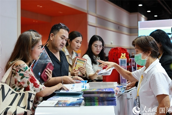 外國觀眾在中國展臺仔細(xì)閱讀赴華旅游介紹，向工作人員咨詢關(guān)于中國美食和景點(diǎn)的詳細(xì)信息。人民網(wǎng)記者 白元琪攝