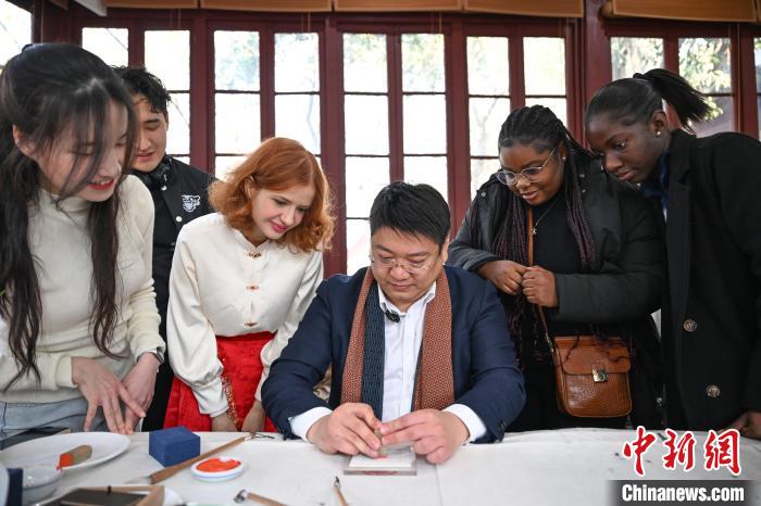 1月20日，篆刻家王臻向外籍留學(xué)生展示篆刻印章。當(dāng)日，來自巴西、馬來西亞、加納、哈薩克斯坦的外籍留學(xué)生在浙江杭州西泠印社體驗(yàn)福貼、春聯(lián)和篆刻，感受古老的中國傳統(tǒng)文化。中新社記者 王剛 攝