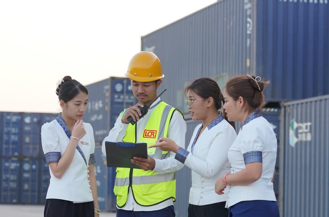 萬象南站貨運(yùn)值班員陳尼啦（左一）與同事在一起討論工作。老中鐵路有限公司供圖