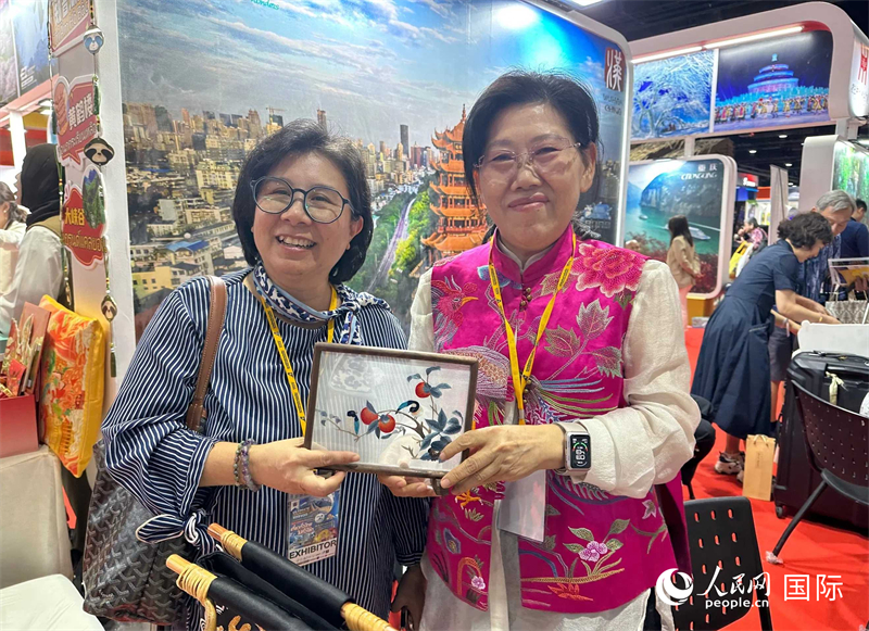 中國“大冶刺繡”傳承人劉小紅（右）參加泰國國際旅游展，向觀眾介紹中國非遺刺繡針法。人民網(wǎng)記者 簡承淵攝