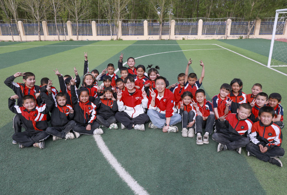 4月23日，在新疆克州阿圖什市哈拉峻鄉(xiāng)謝依特小學(xué)，支教教師王俊文（中左）、李軻凡（中右）和學(xué)生在一起。