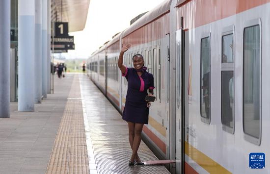 5月31日，在蒙內(nèi)鐵路內(nèi)羅畢站，一名乘務(wù)員在即將開(kāi)往蒙巴薩的E2次列車(chē)旁等候乘客。新華社記者 李亞輝 攝